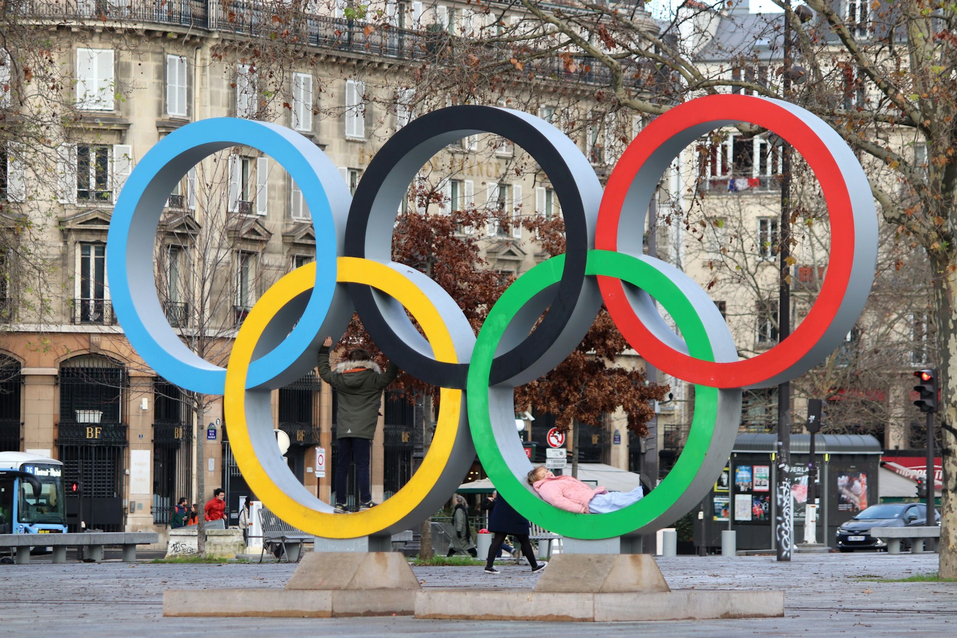 The olympic rings stand in a city square.
